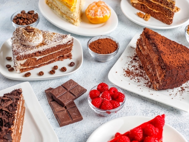 Сладкие куски торта на столе с шоколадом и ягодами