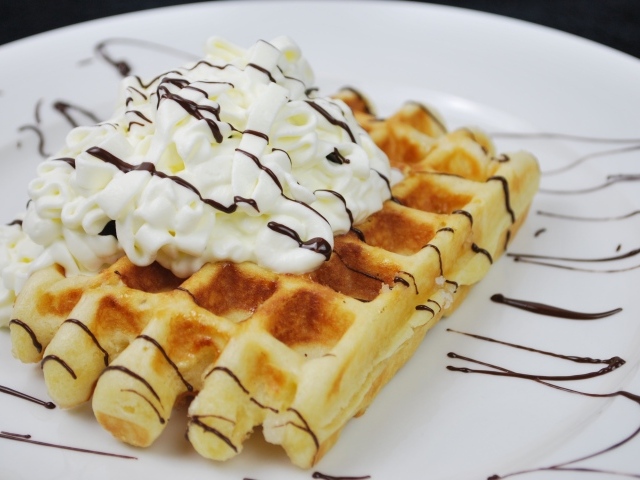 Сладкая вафля со сливками на белой тарелке