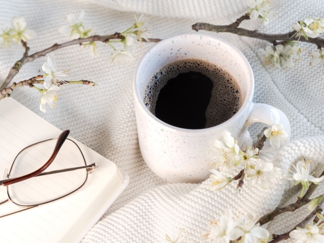 Чашка кофе с цветущей веткой на столе
