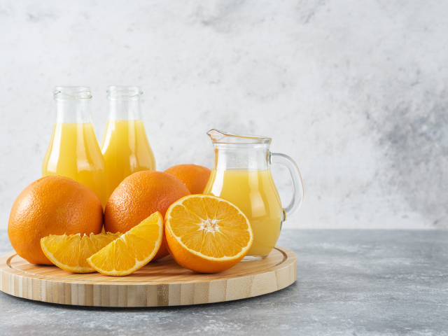 Свежевыжатый сок на столе с апельсинами