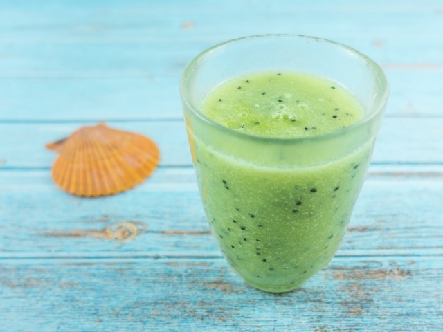 Фруктовый зеленый смузи на голубом столе