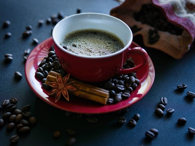 Красная чашка кофе на столе со специями и зернами