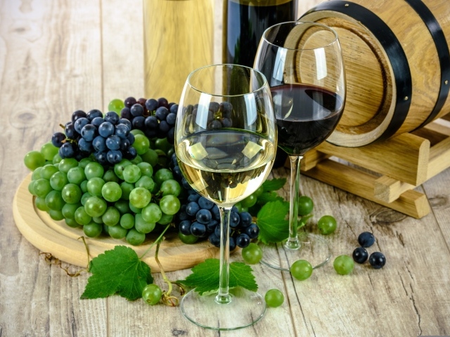 Два бокала вина на столе с виноградом и бочкой