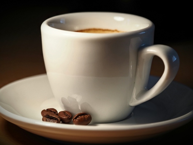 Белая чашка кофе с зернами крупным планом