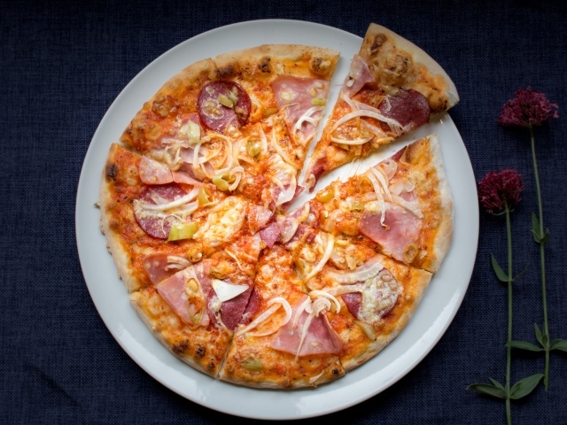 Нарезанная пицца на белой тарелке