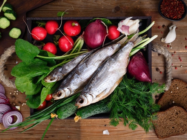 Сушеная рыба на столе с овощами и зеленью 