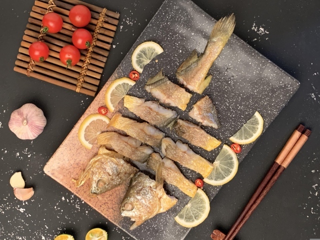 Жареная рыба на столе с помидорами и лимоном