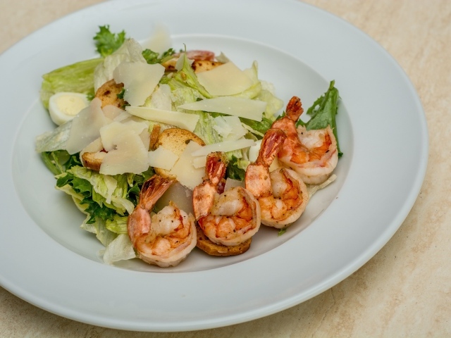Креветки на тарелке с листьями салата