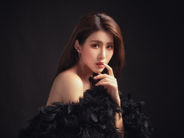 Девушка азиатка в боа на черном фоне