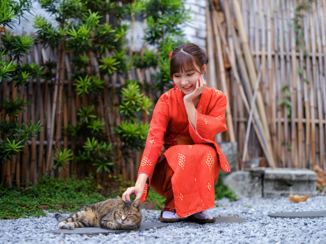 Девушка азиатка в красном платье гладит кота