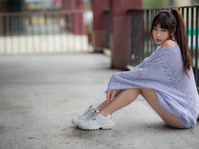 Девушка азиатка в свитере и белых кроссовках 