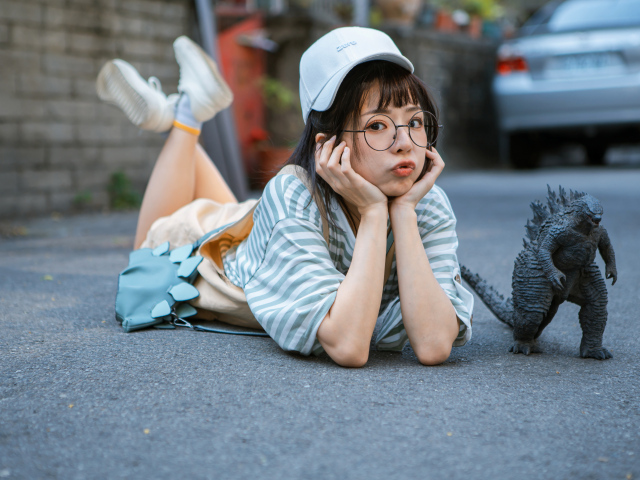 Девушка азиатка с фигуркой годзиллы