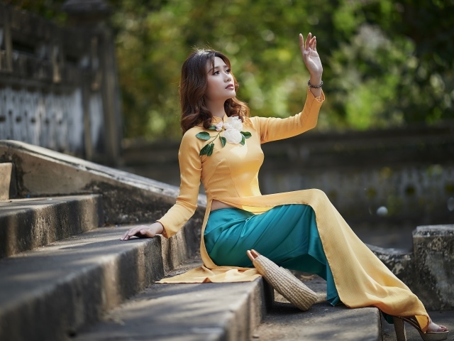 Красивая девушка азиатка сидит на ступеньках