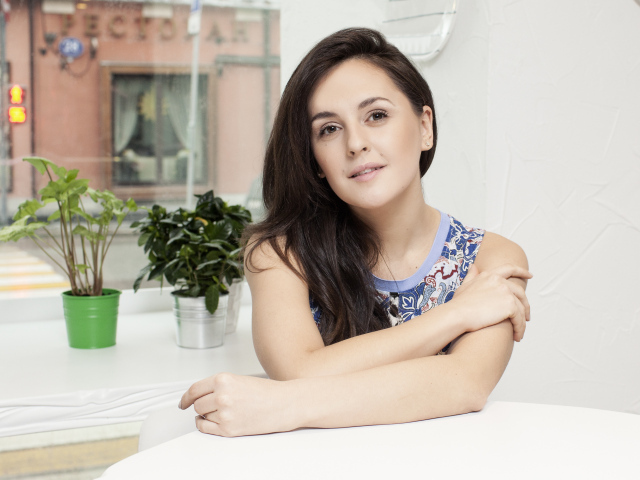 Красивая девушка брюнетка сидит за столиком в кафе 