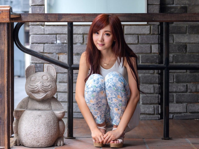 Милая девушка азиатка позирует со статуэткой