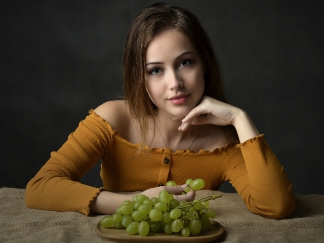 Милая шатенка ест белый виноград