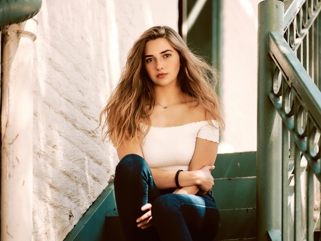 Милая девушка брюнетка сидит на ступеньках