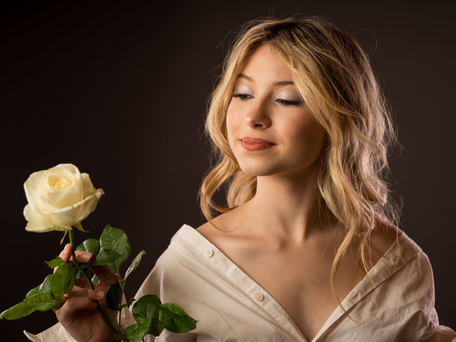 Милая девушка в рубашке с розой в руках