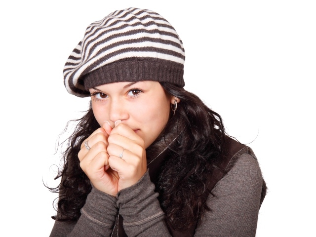 Девушка в теплой полосатой шапке на белом фоне
