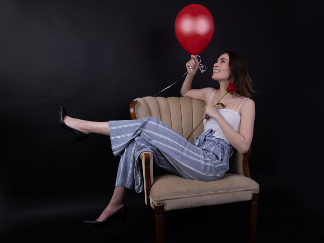 Девушка с шариком и розой сидит в кресле