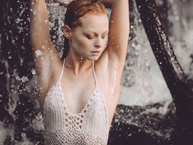 Рыжеволосая девушка в брызгах воды