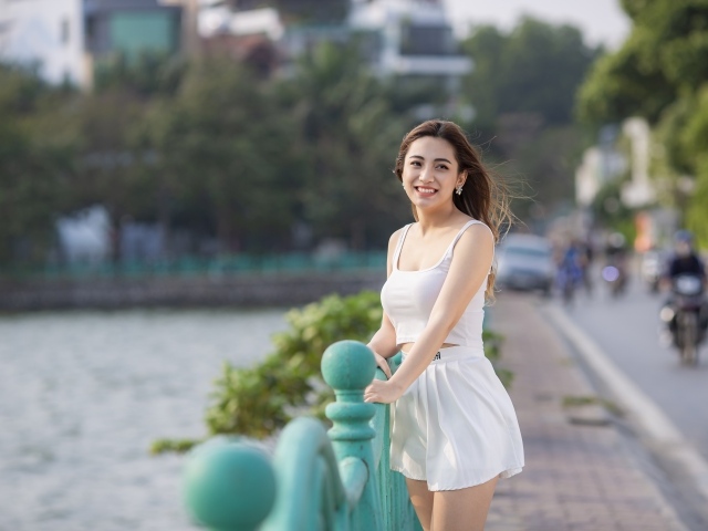 Улыбающаяся девушка азиатка в белом летнем костюме