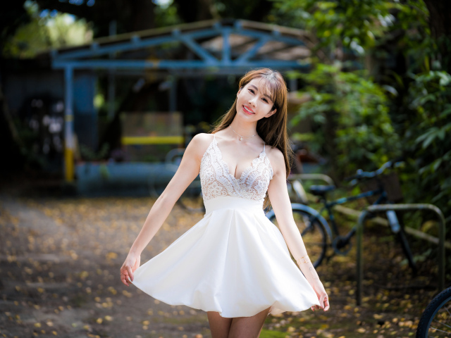 Улыбающаяся азиатка в белом платье в парке