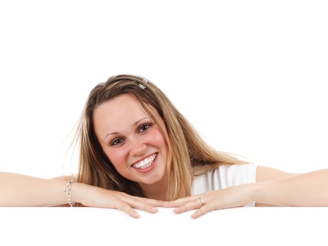 Улыбающаяся девушка сидит на белом фоне