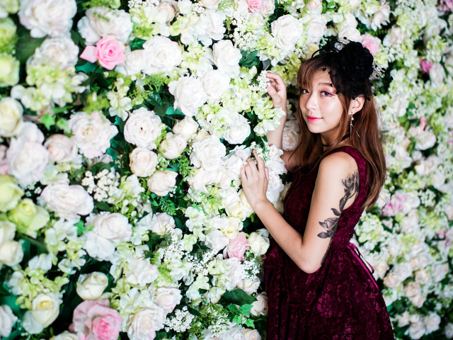 Молодая азиатка на фоне стены с розами