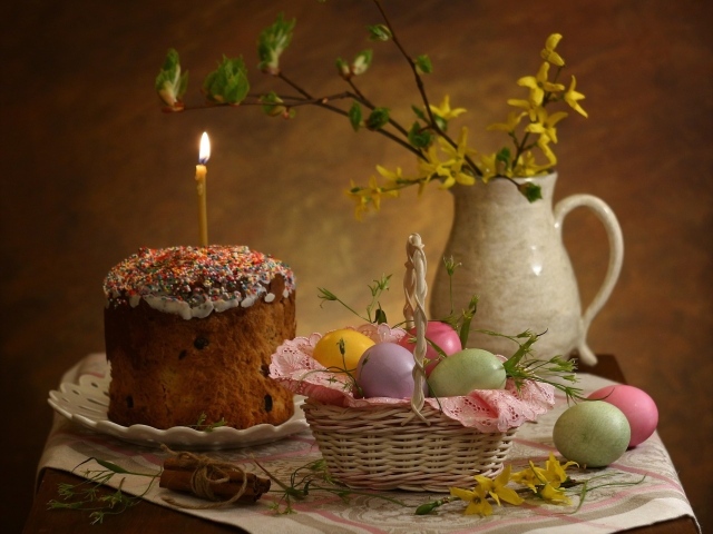 Кулич со свечой и крашеными яйцами на столе на Пасху