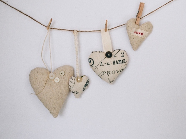 Сердечки из ткани на веревке на серой стене