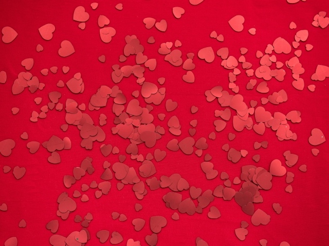 Маленькие бумажные сердечки на красном фоне