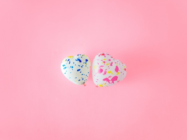 Два шарика в форме сердца на розовом фоне