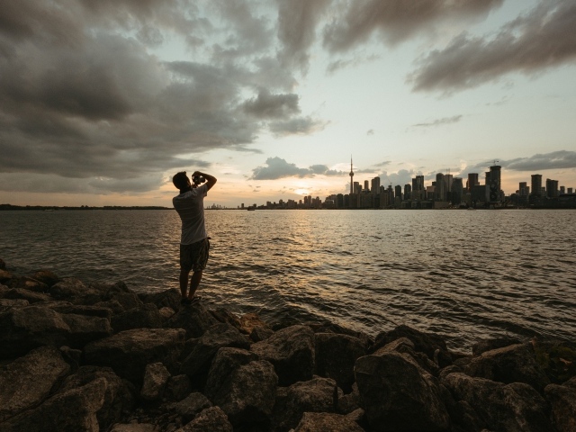 Мужчина делает фото города у моря