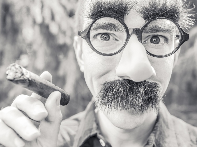 Мужчина в очках с сигарой в руке