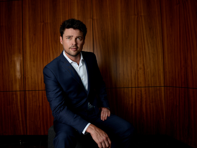 Актер Карл Урбан в костюме на фоне стены