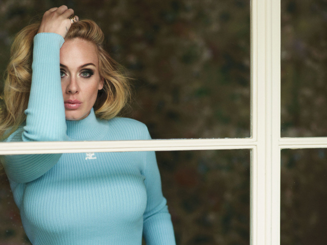 Певица Адель стоит у окна