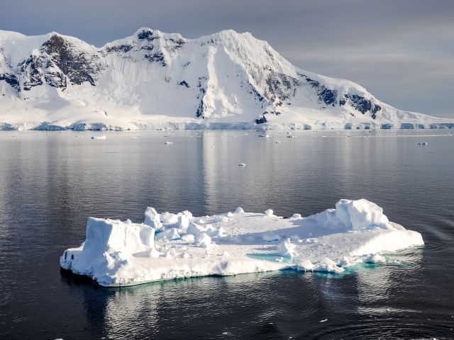 Холодный айсберг в воде у заснеженных гор, Антарктика