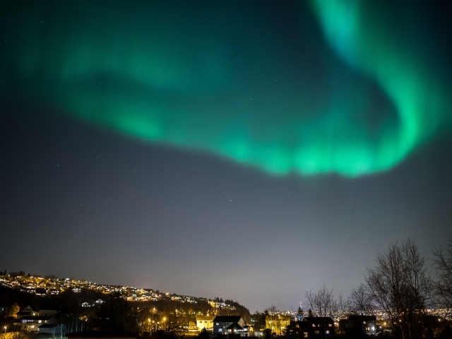 Зеленое полярное сияние в небе над ночным городом