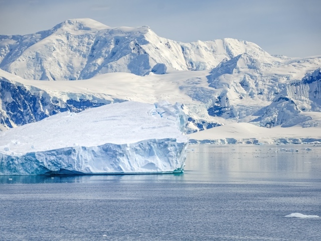 Большой айсберг у берега с заснеженными горами