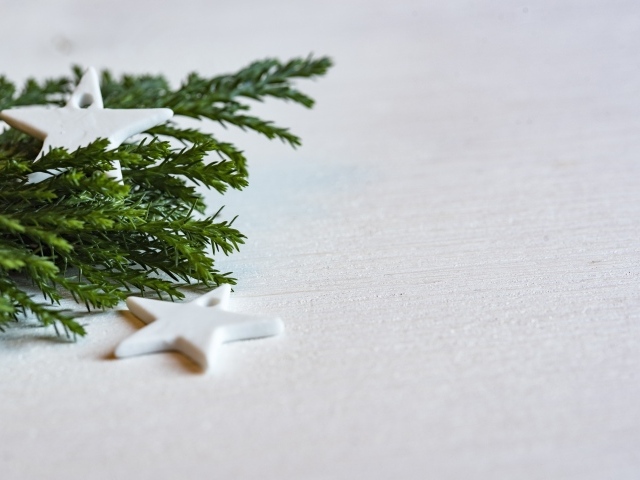 Звезды и ветка ели на белой поверхности 