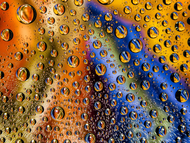 Капли воды на разноцветном стеклянном фоне