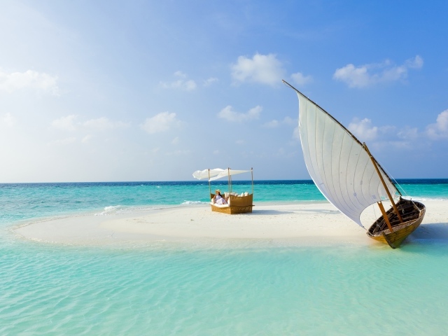 Лодка стоит на белом песке у голубого океана