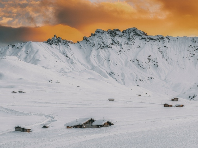 Красивая заснеженная гора под оранжевым небом