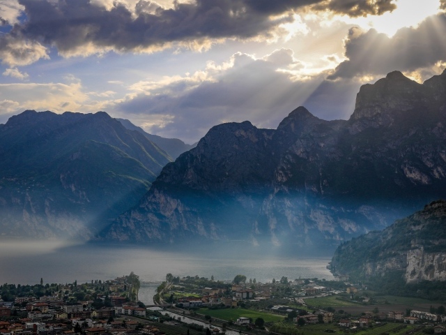 Лучи солнца покрывают горы и город 