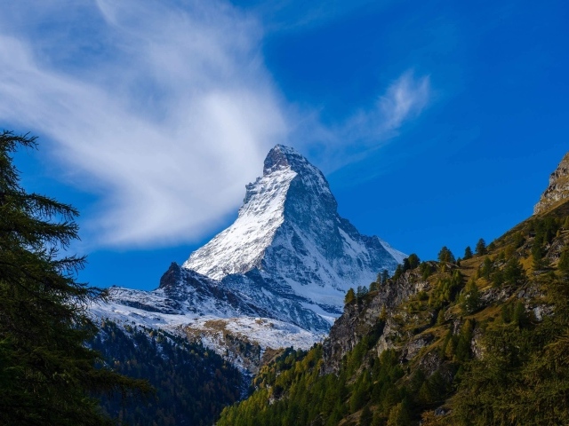 Вид на высокую заснеженную гору под голубым небом
