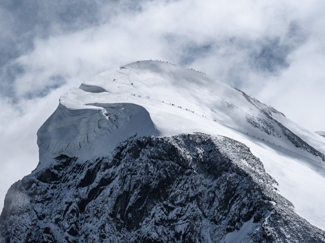 Вид на заснеженную вершину горы под белыми облаками