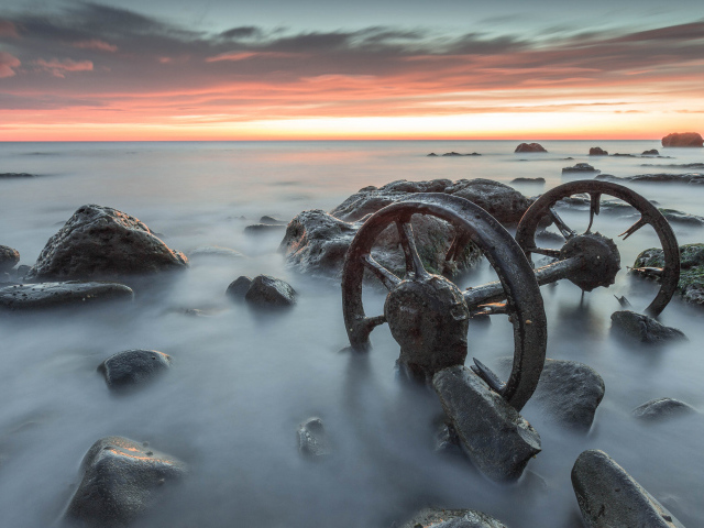 Старые колеса лежат в воде с камнями