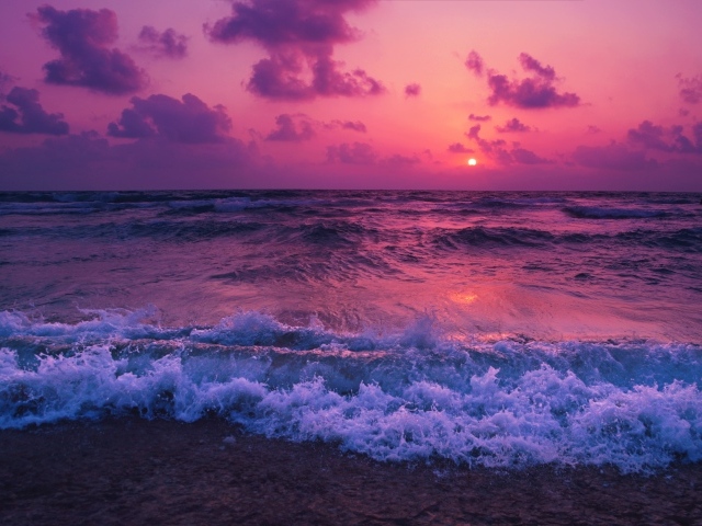 Белые морские волны на берегу в лучах розового заката