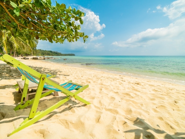 Шезлонг стоит на горячем песке у моря летом